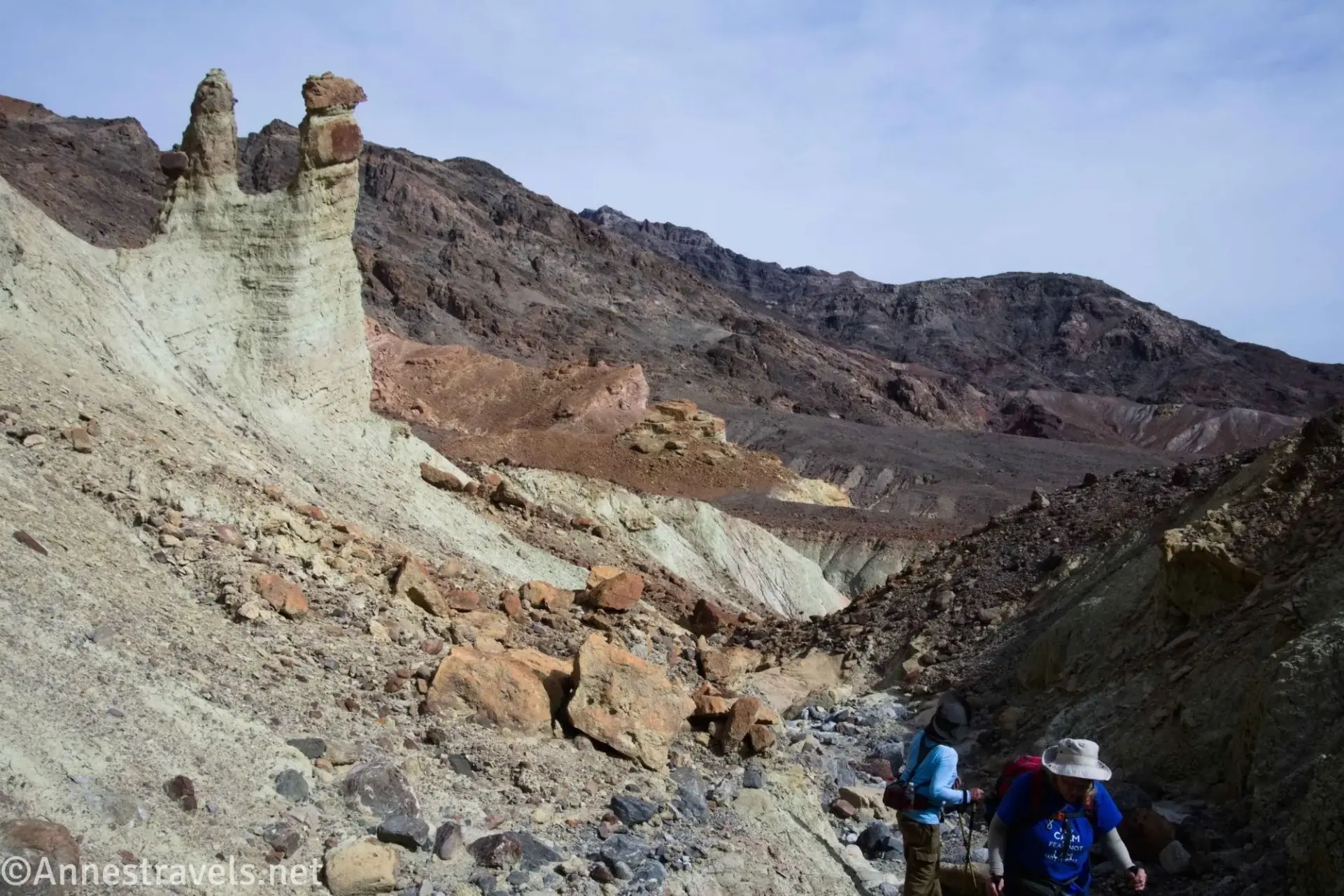 Pinnacle Fork Two hikers in a barren gully beside two rock towers