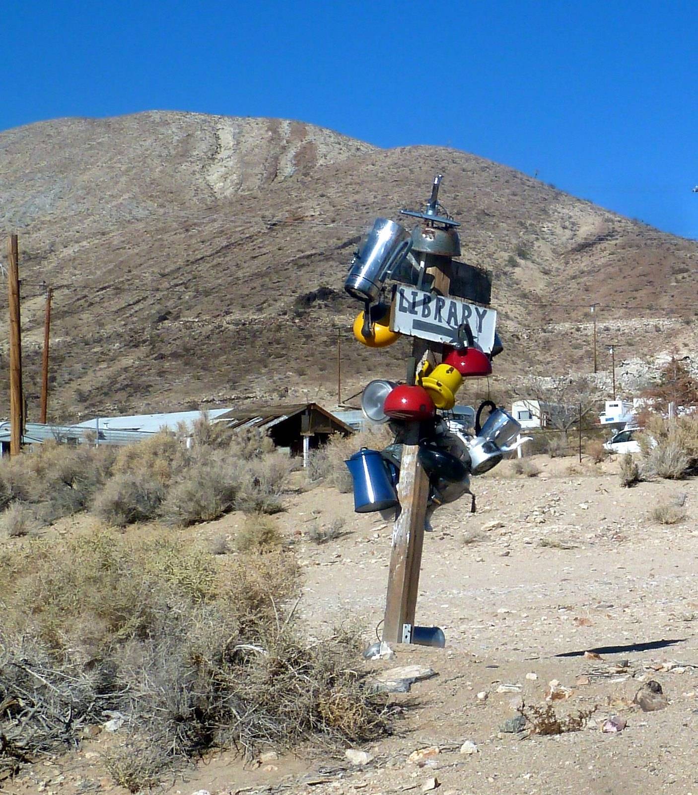 Library Sign A sign for a library and a post covered with colorful teapots in the desert