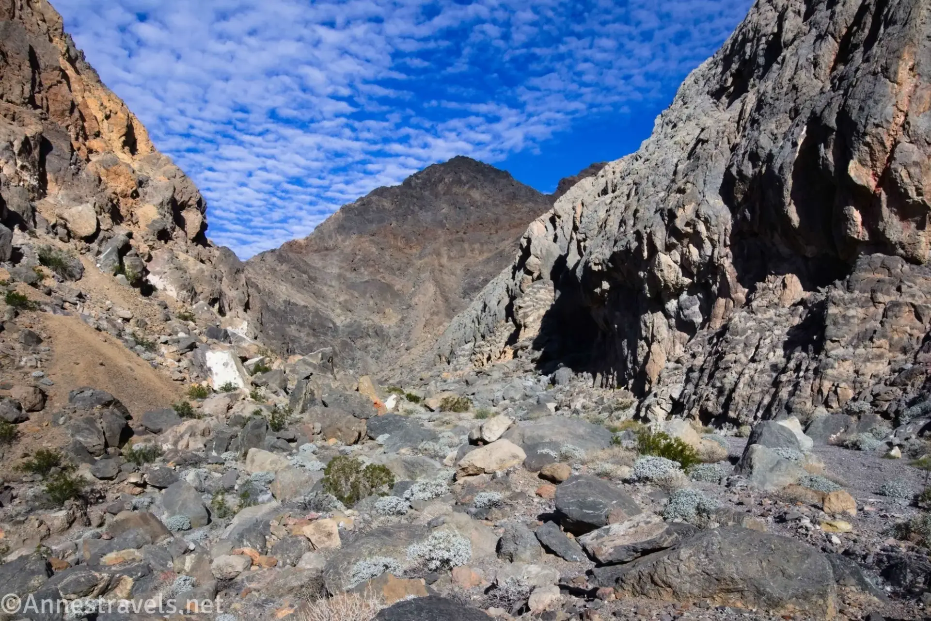 Approaching the Mouth of Slit Canyon Rocks in the mount of a desert canyon below blue skies with clouds