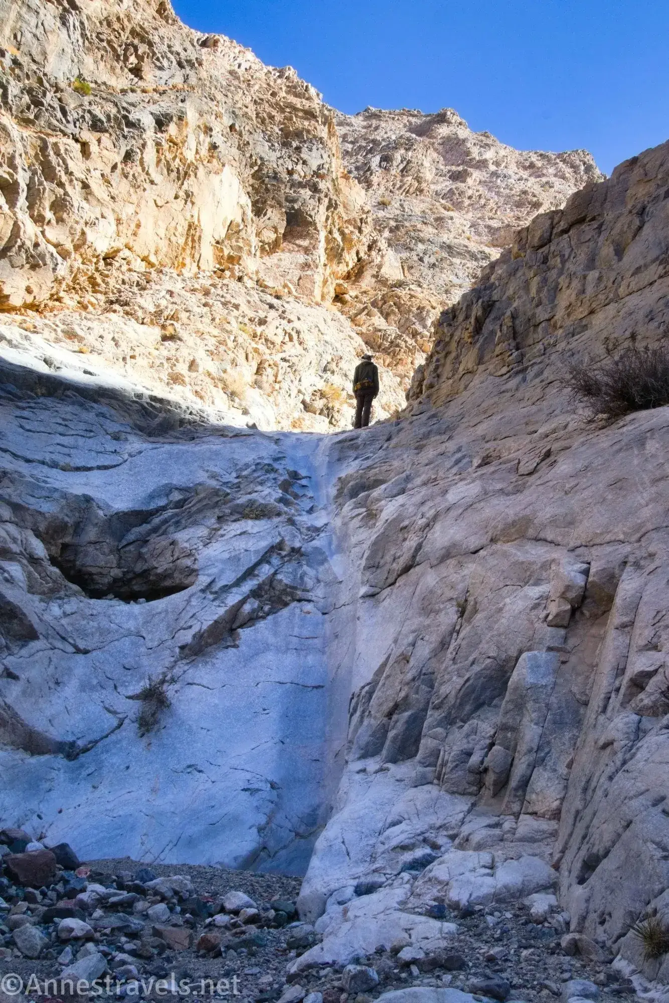 A smooth dryfall A hiker atop a smooth dryfall in a rocky canyon