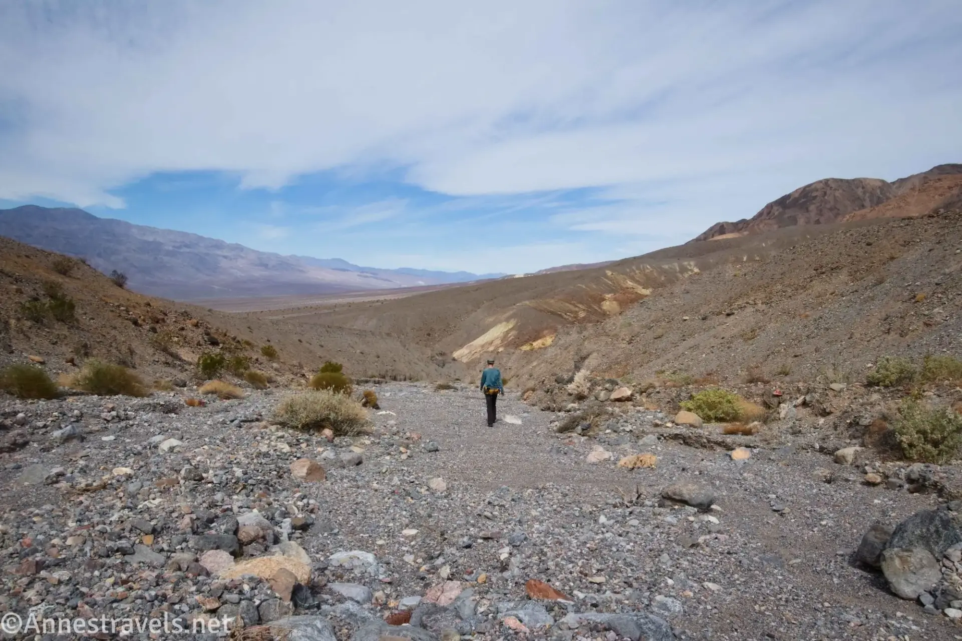 Walking the Wash to The Cauldron A hiker walking in a gravel wash with mountains beyond
