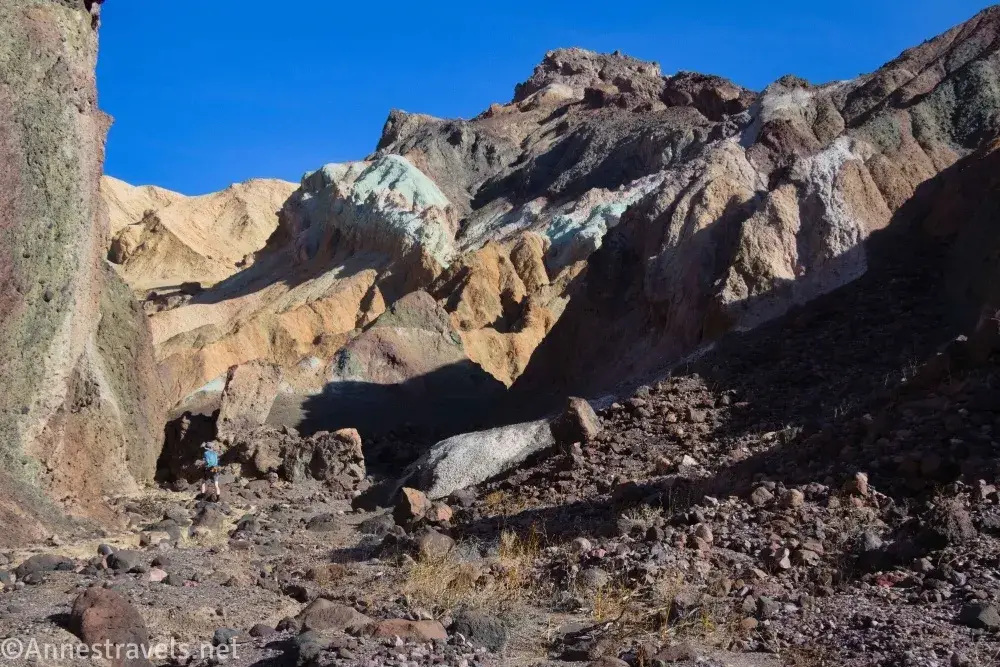 Colorful Cliffs in the South Fork of Desolation Canyon A hiker in a canyon below colorful cliff walls and a brown hill