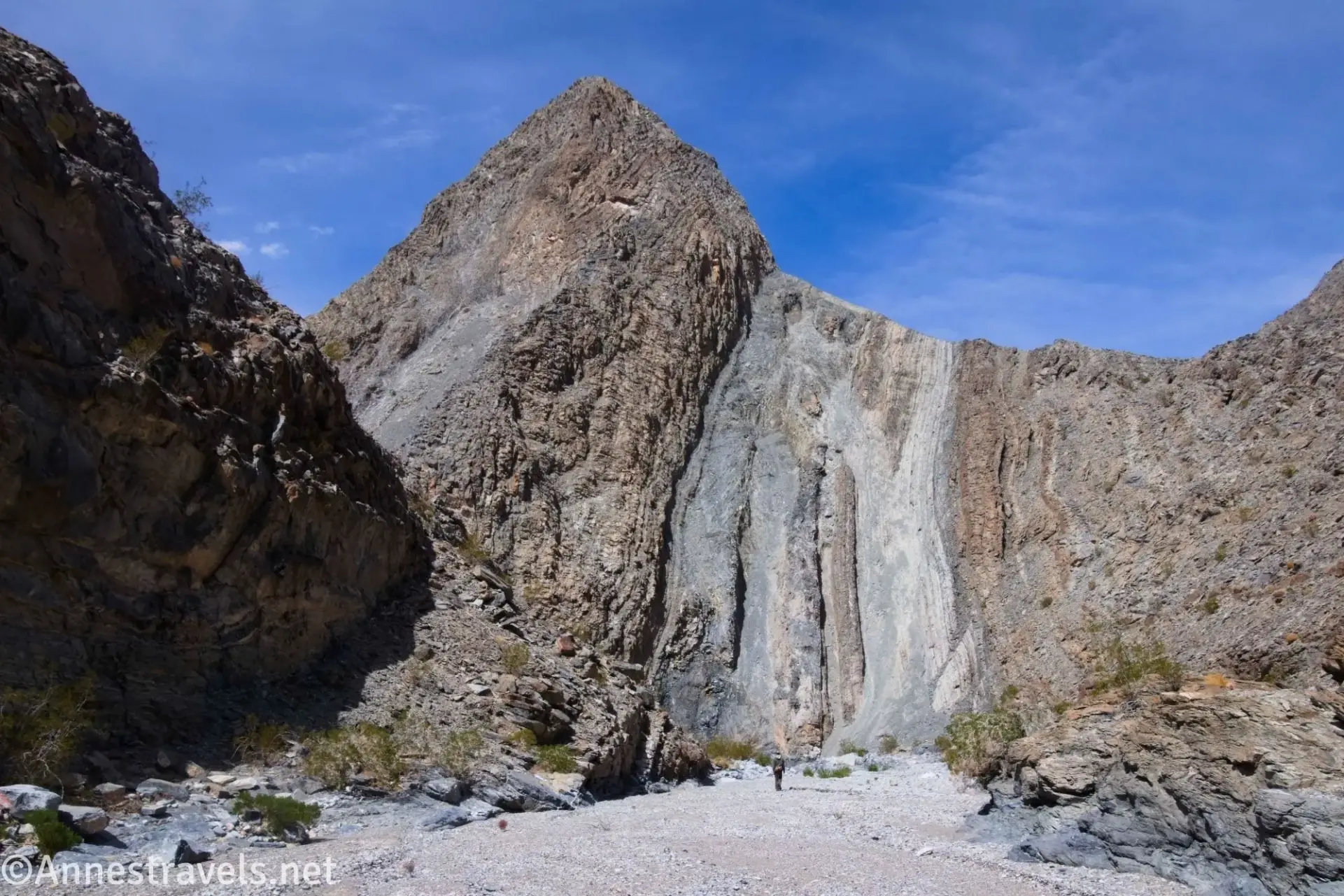 Hiker below a Striped Wall Striped rocky wall of a canyon