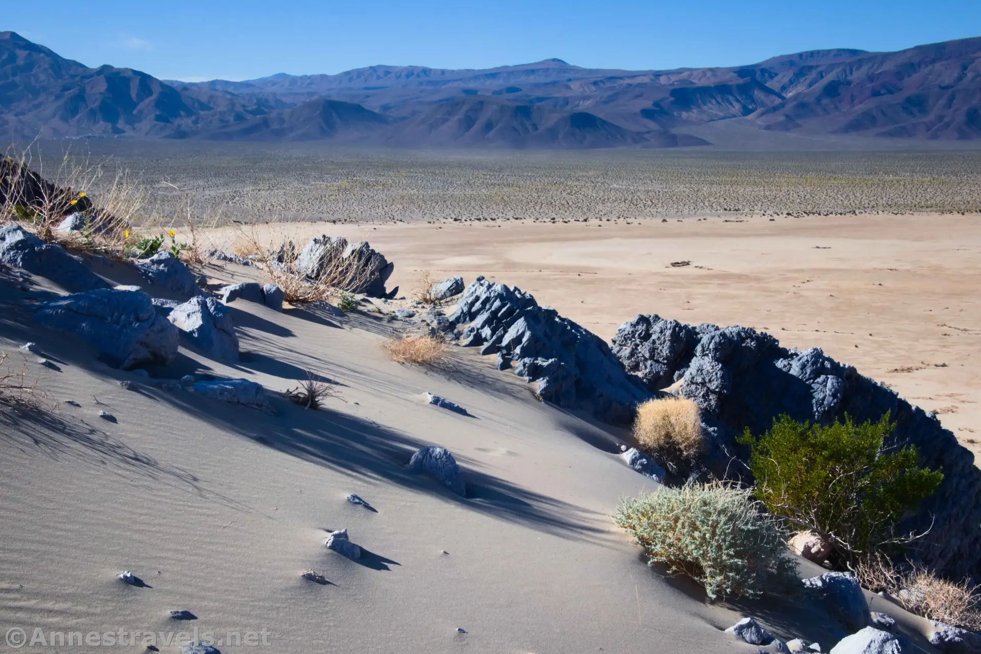 Sand on Lake Hill Sand and rocks on the hillside above playa and a desert plain and distant desert mountains