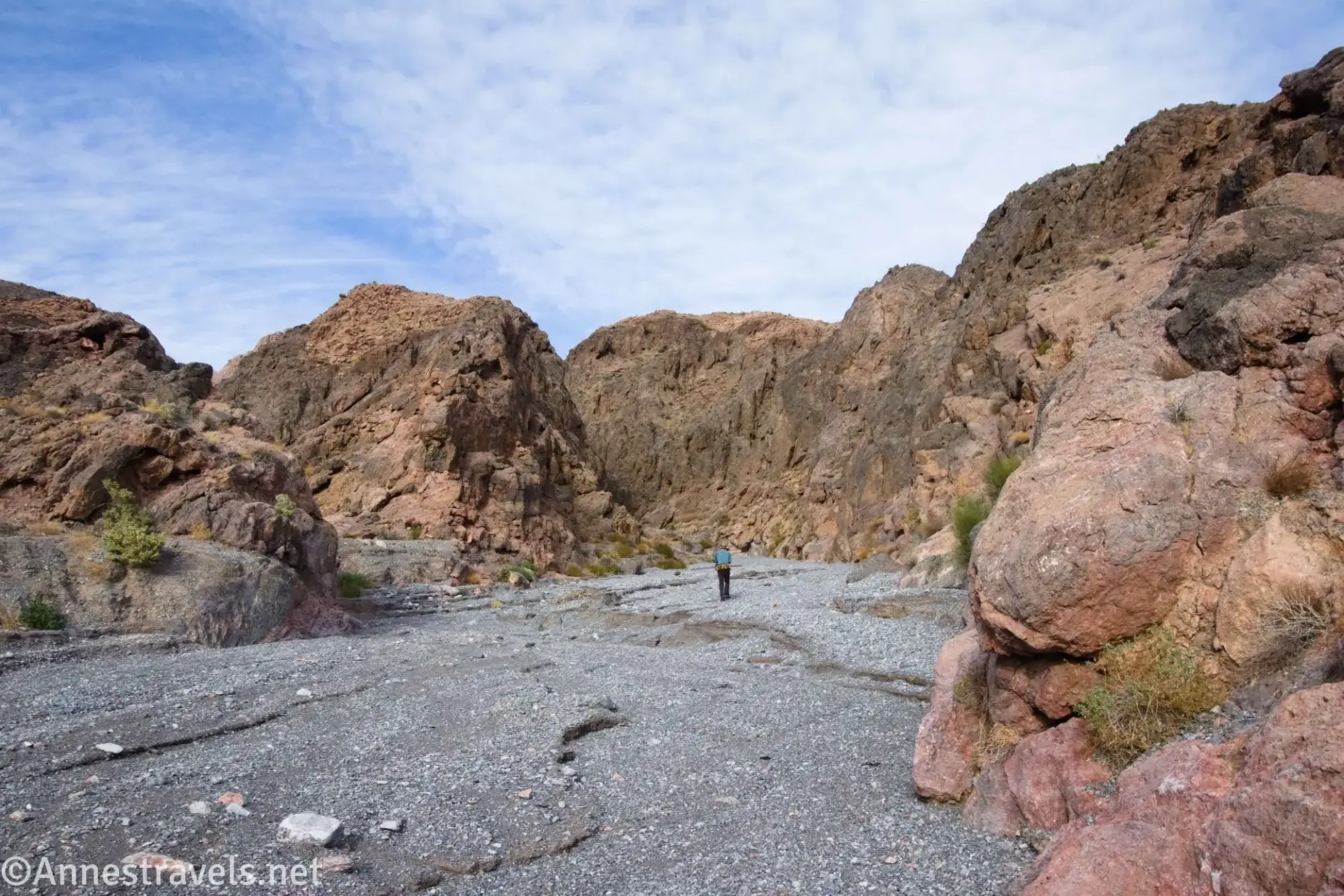 Wide Section of Canyon A hiker in a gravelly wash between colorful canyon walls