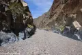 Hikers in a sheer, straight canyon with rock walls and a gravel floor