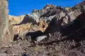 Colorful Cliffs in the South Fork of Desolation Canyon A hiker in a canyon below colorful cliff walls and a brown hill
