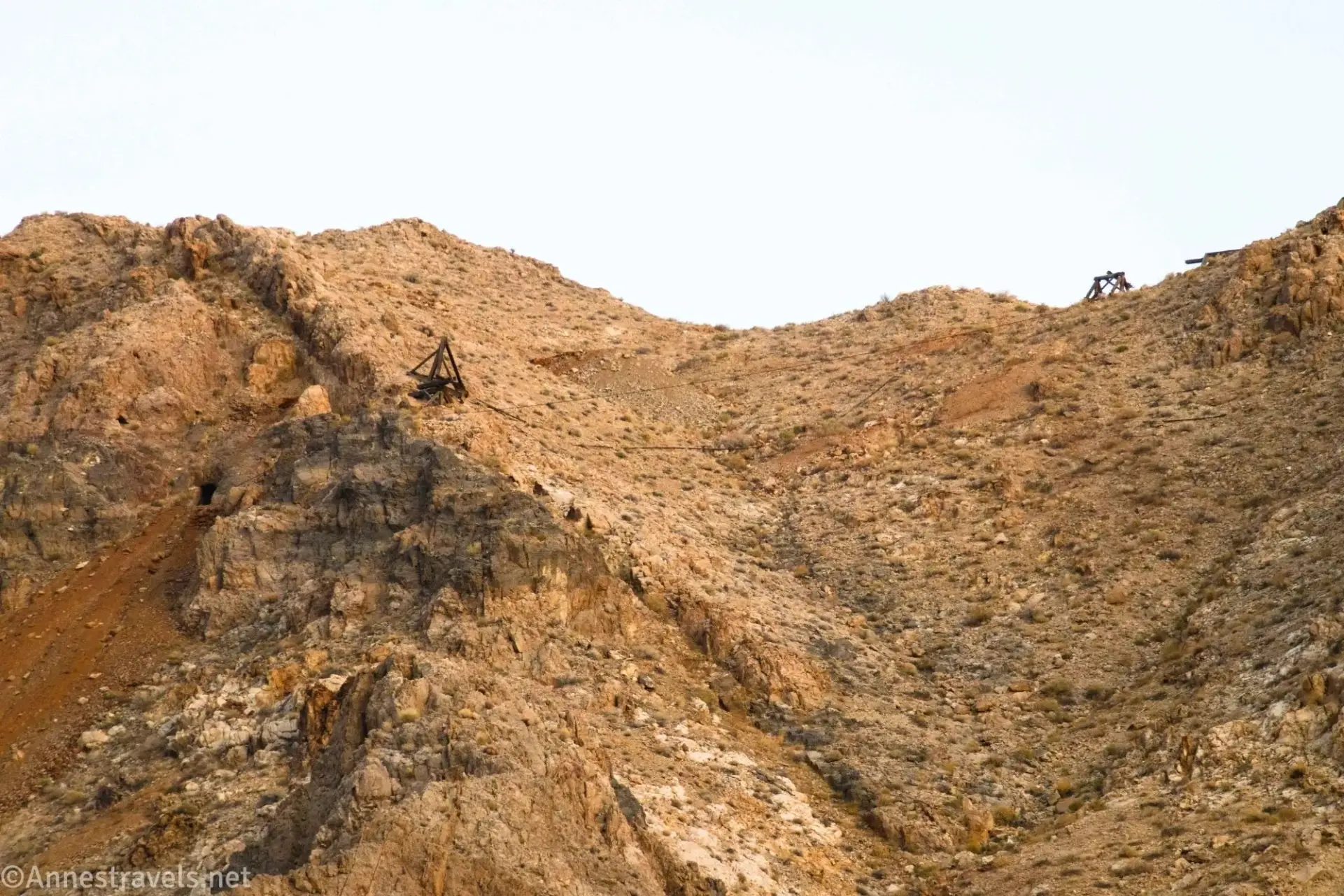 A light brown hillside with a few old tramway towers and the mine on the left