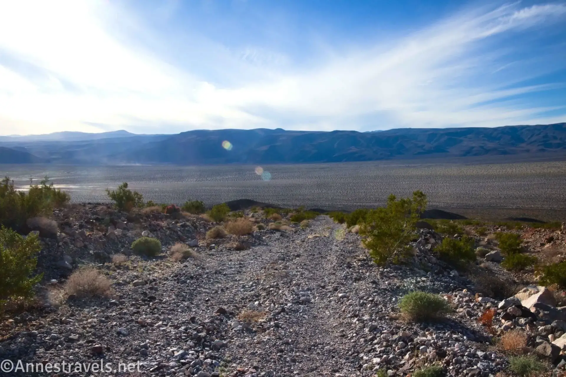 A gravel road leading down toward a desert plain