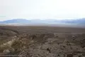 Ridgline Views over Chaos Fork A rugged desert landscape including colorful badlands and distant hazy mountains