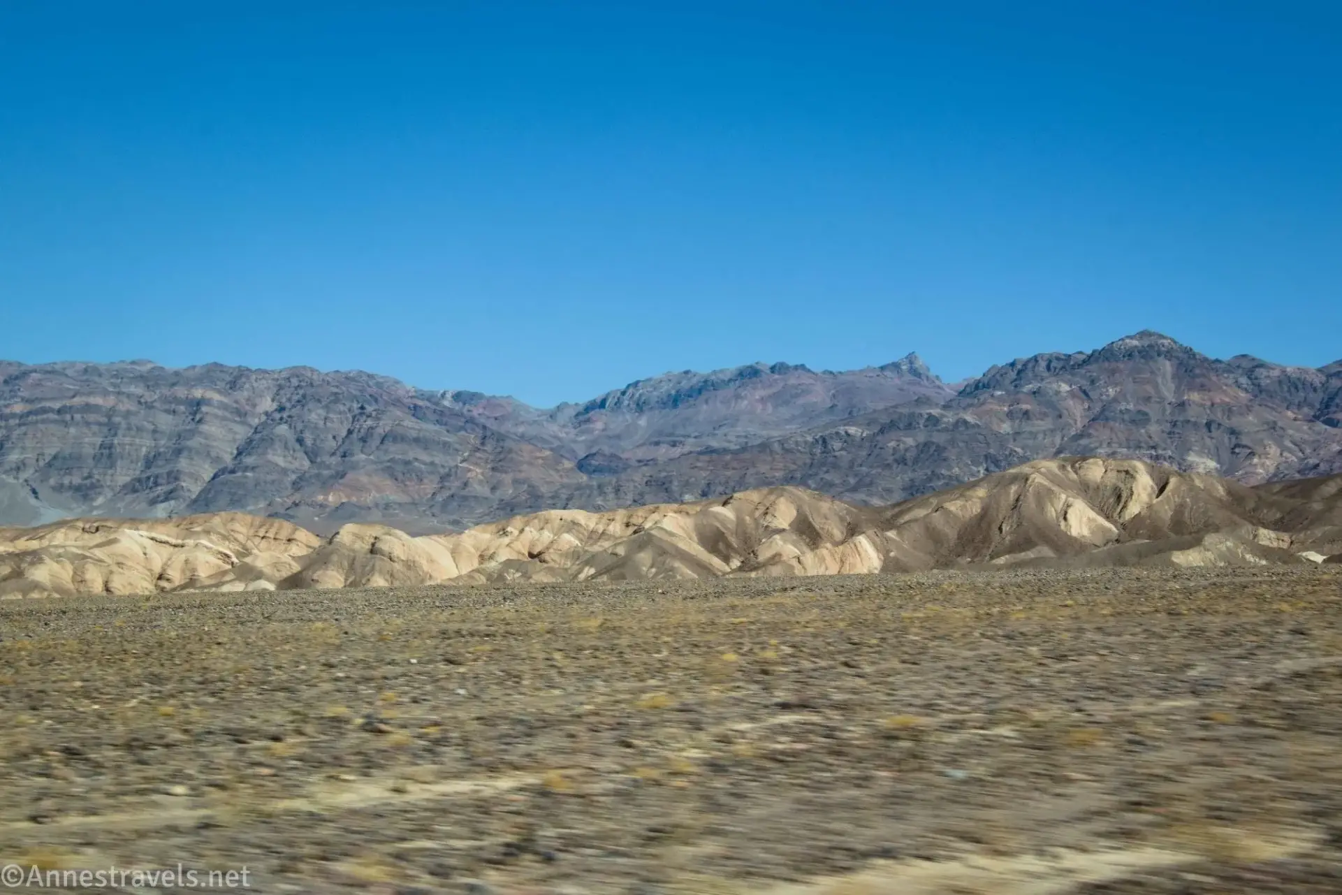 Striped desert mountains above striped tan and brown badlands 