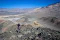 Hiking Down Lake Hill A hiker on a rocky slope looking down at a desert with hills and playa and distant mountains