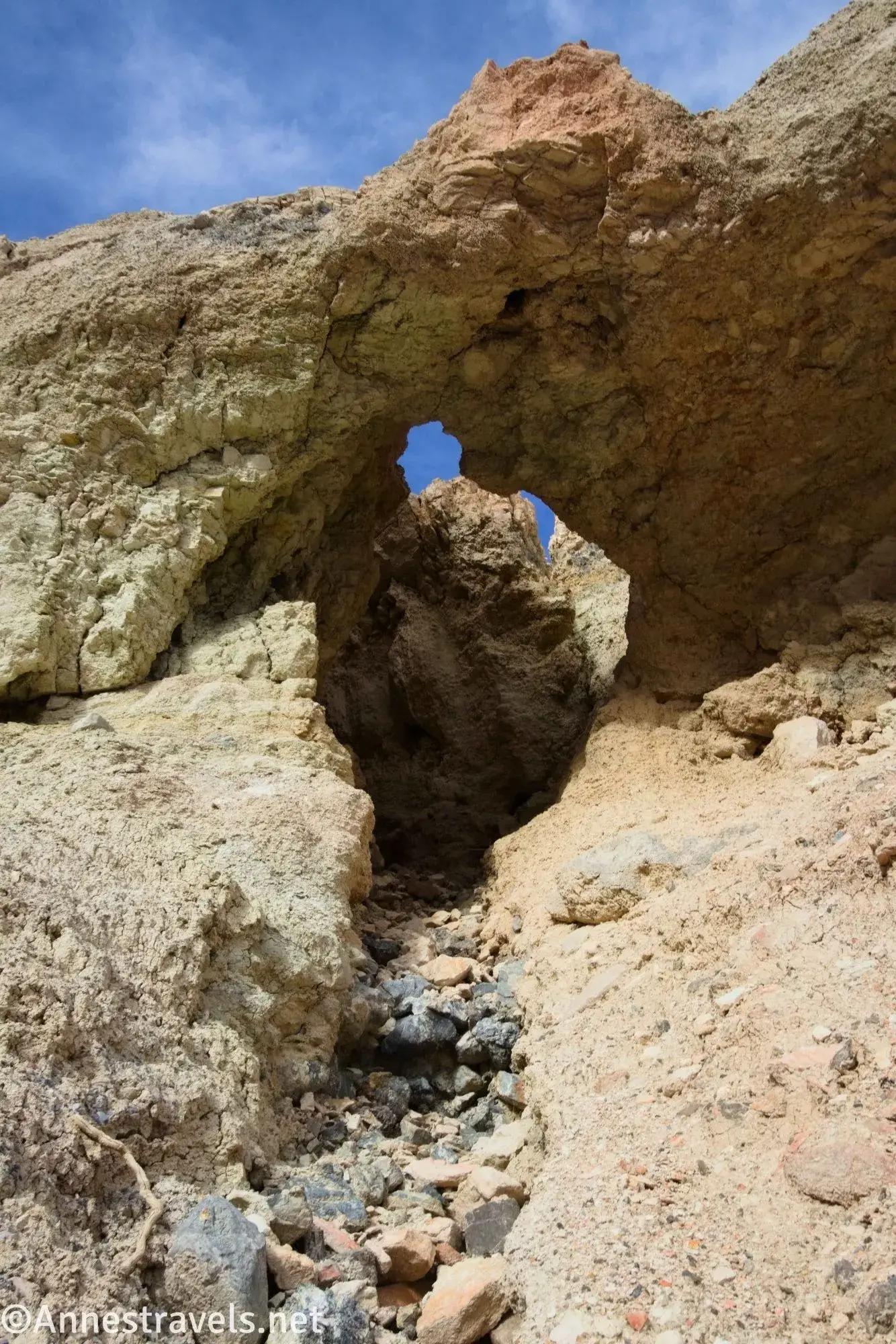 A small arch and rocks in a yellow rock