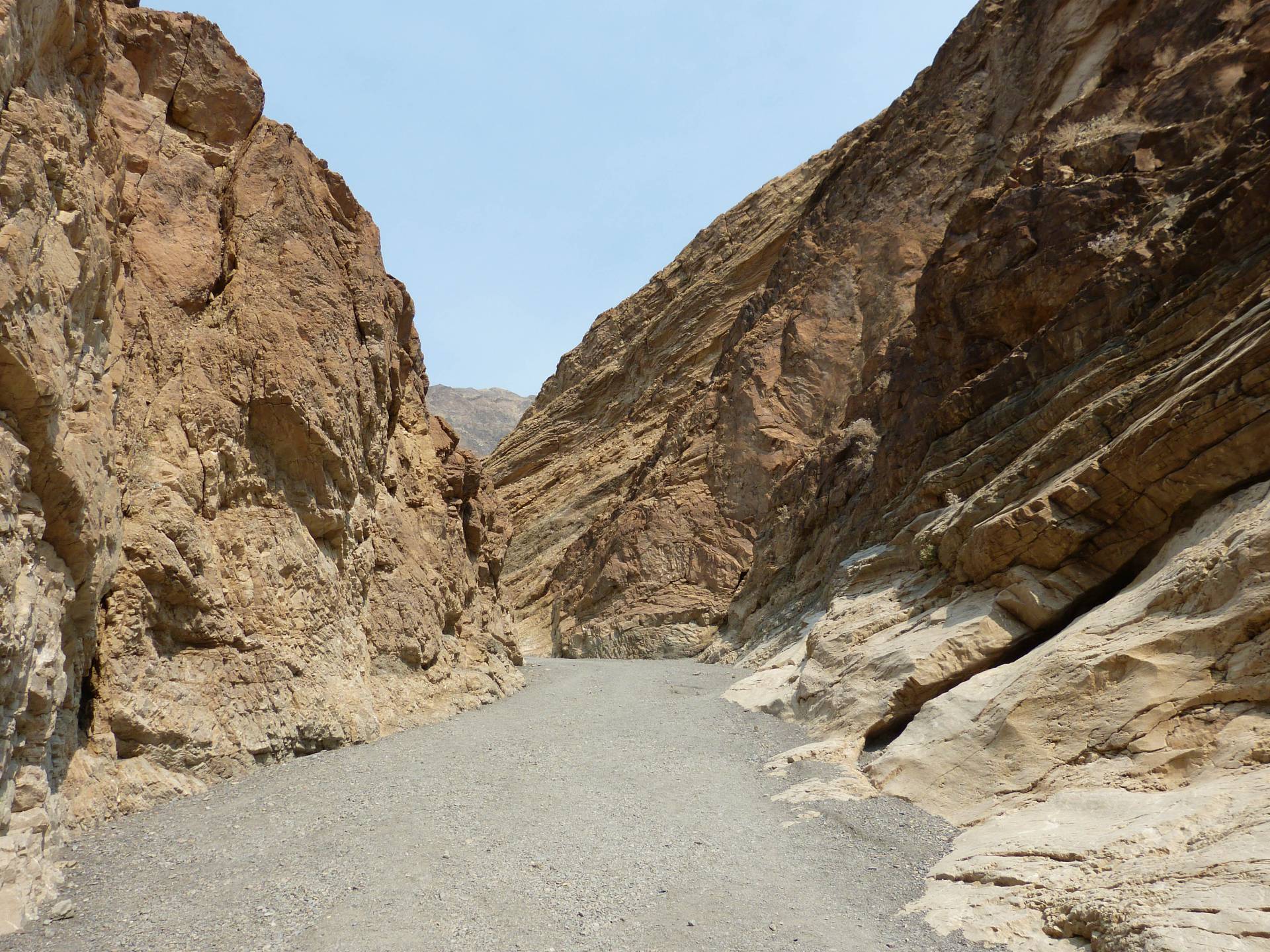 Brown canyon walls around a wide gravel wash