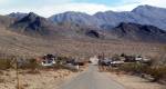 Darwin Ghost Town Paved road leading into a small town below mountains