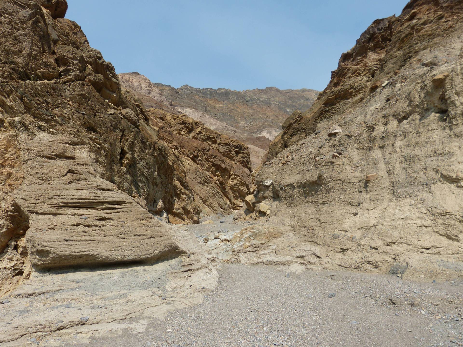 Brown canyon walls rise around a  gravel wash