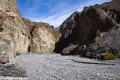 Lower Corridor Canyon A wide, gravely wash with brown cliffs of a canyon