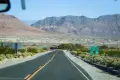 A paved road and signs below desert mountains