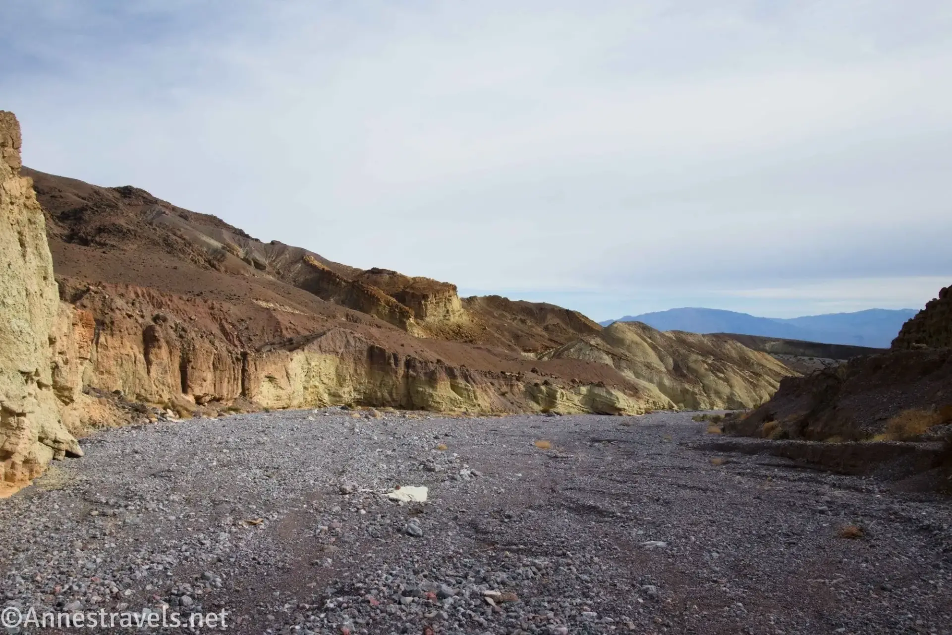 Yellow, red, and brown walls of a wide wash with a gravel bed