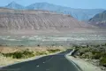 A paved road heading for desert hills and mountains