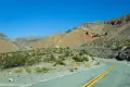 An orange cone beside a road with colorful desert hills in the background