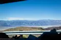 Distant mountains across a desert valley with a guardrail in the foreground
