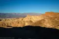 Manly Beacon and striped badlands in front of gray mountains in the early morning light from Zabriskie Point in Death Valley National Park