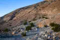 A rough gravel roadbed below a dry desert hill