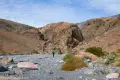 Between the Narrows A hiker in a gravelly wash below brown desert cliffs