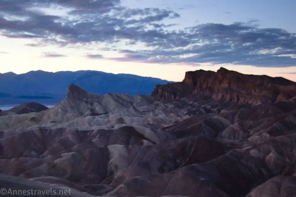 Darkness settles on Manly Beacon and badlands after sunset with clouds above at Zabriskie Point