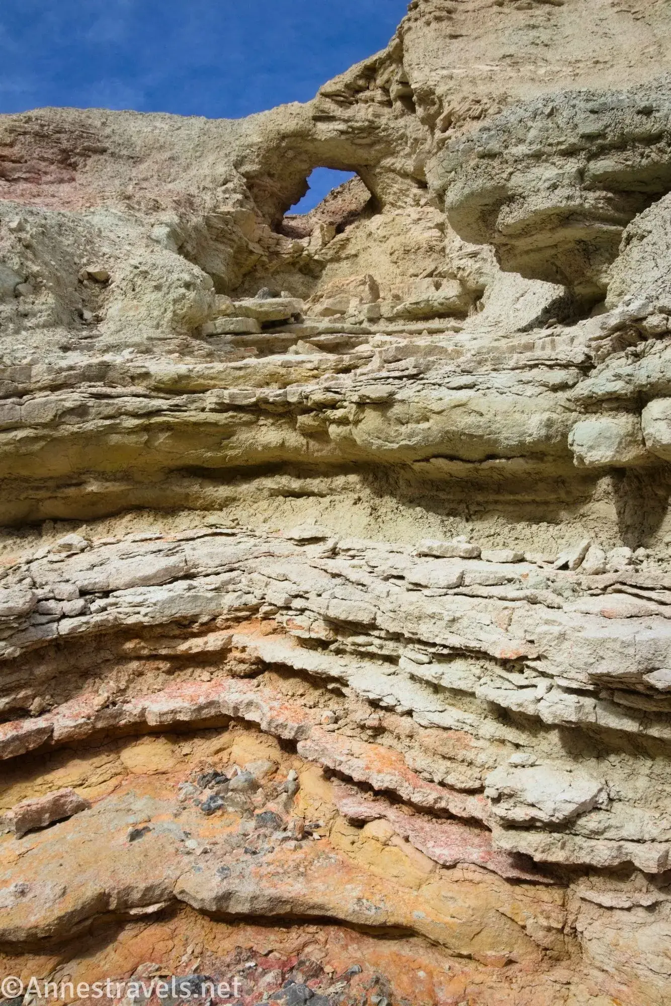 A small arch and layers of yellow and orange rock