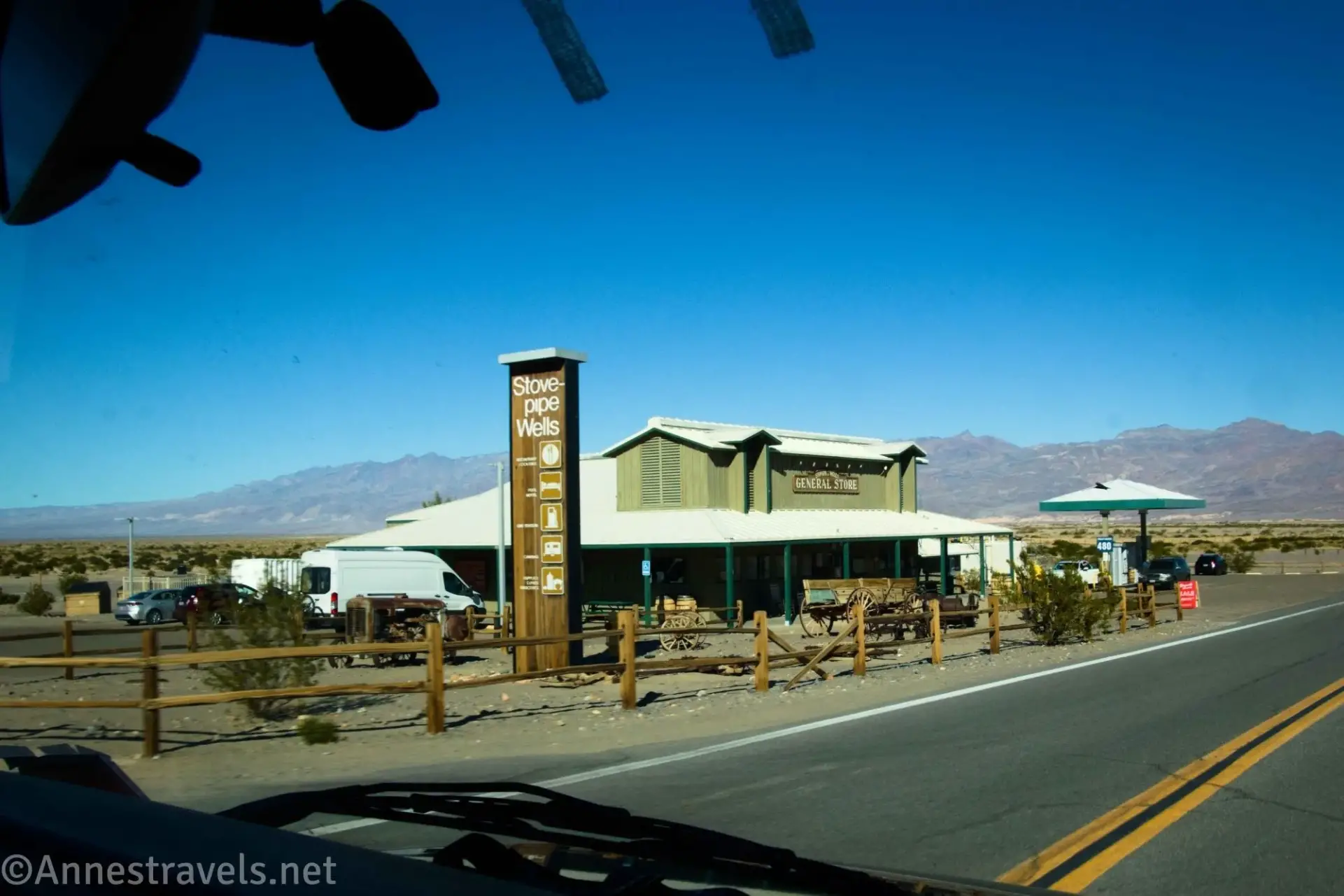 Split rail fence, building, van, and gas station in the desert